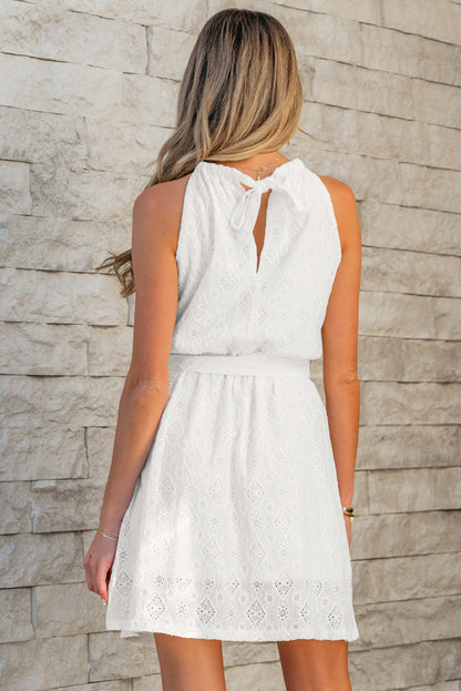 Robe mini blanche sans manches en dentelle avec nœud, taille nouée dans le dos et découpes.